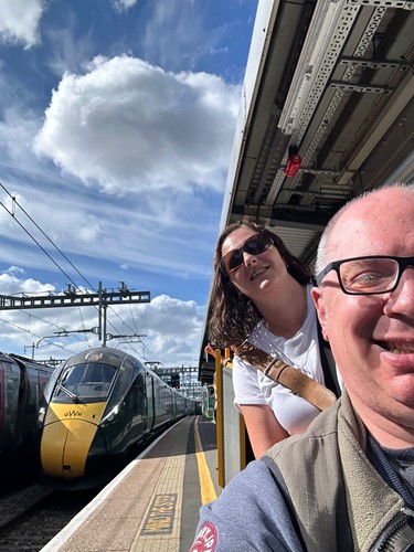 Carer and client on a business trip stood next to a train