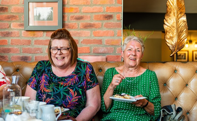 CareGiver and client in café eating cake and laughing