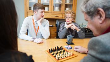 Homecare worker playing chess in community with client