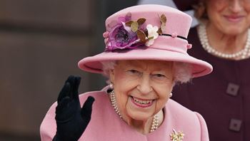 Picture of Queen Elizabeth II wearing a pink dress and holding flowers in left hand