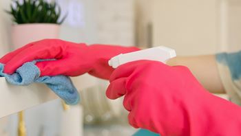 Hands in Washing Up Gloves cleaning a Shelf