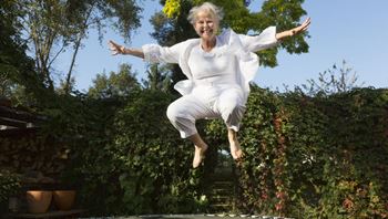 Elderly Lady Jumping on a Trampoline Smiling