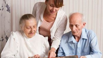 Elderly Couple with Care Assistant Smiling at Old Photos
