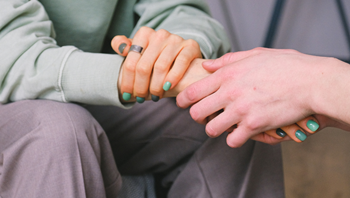Two people holding hands; giving support.